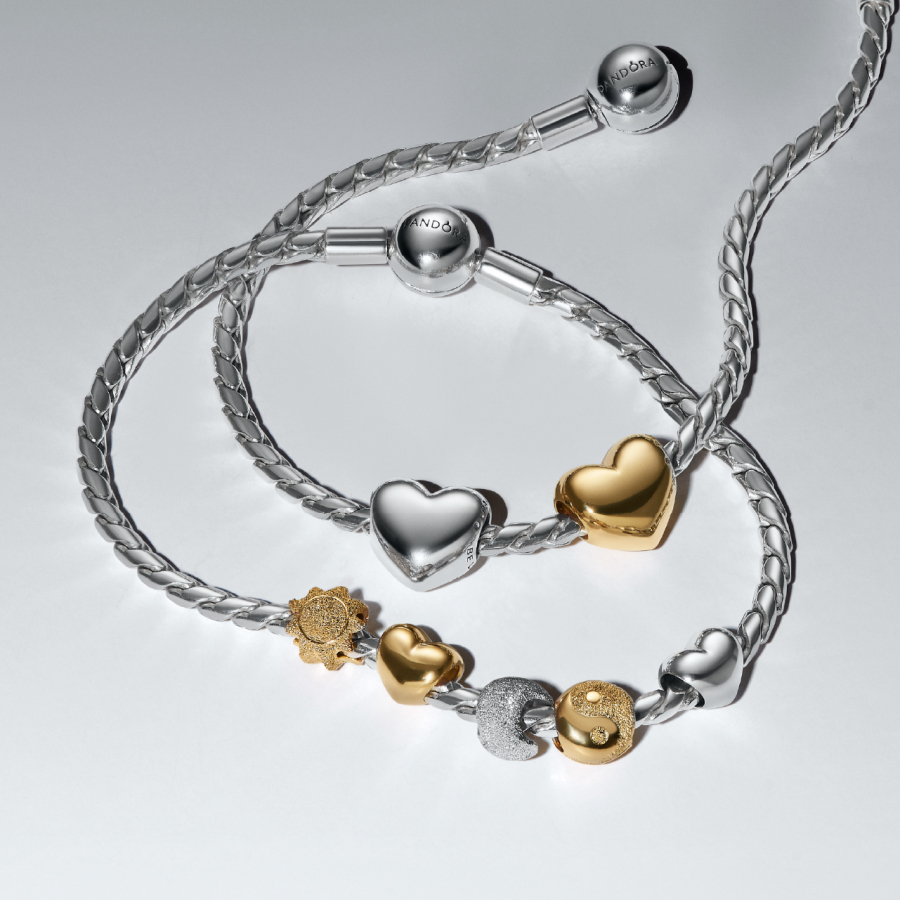 There is a silver charm bracelet with various gold and silver charms from Pandora.
